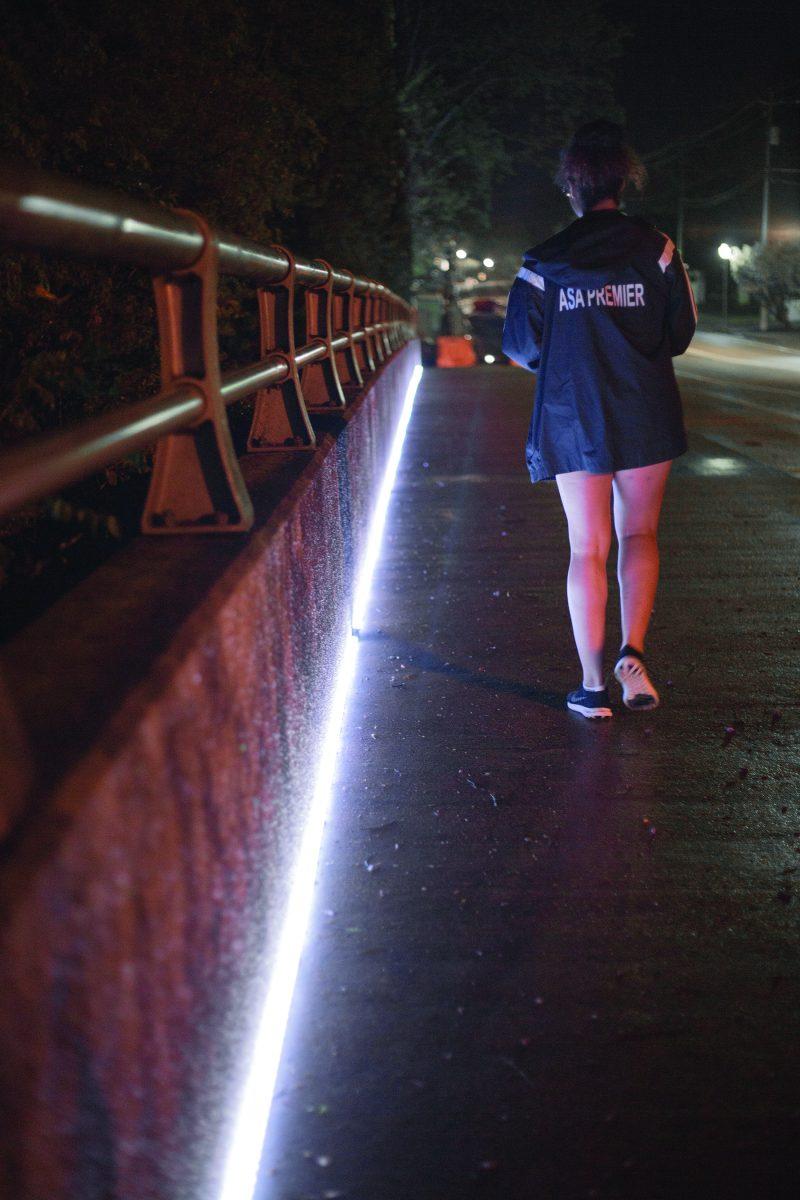 Freshman Jasmine Chin, an Aerospace Engineering major, walks along the University Drive Bridge which is newly lit by GLO lights.