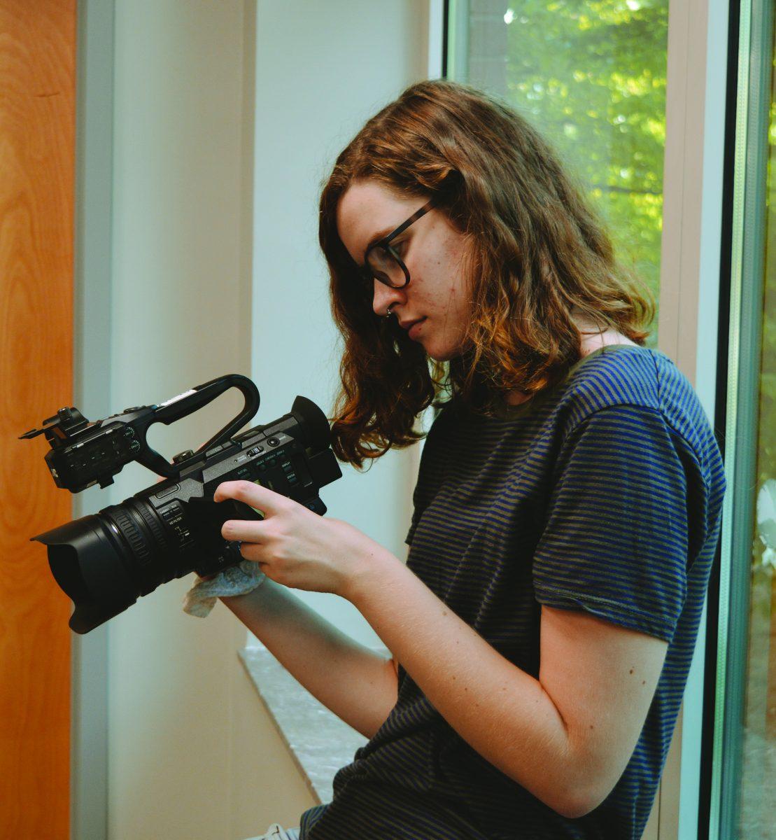 Caroline Matheny, president of the new film club “The Scene,” adjusts a video camera. 