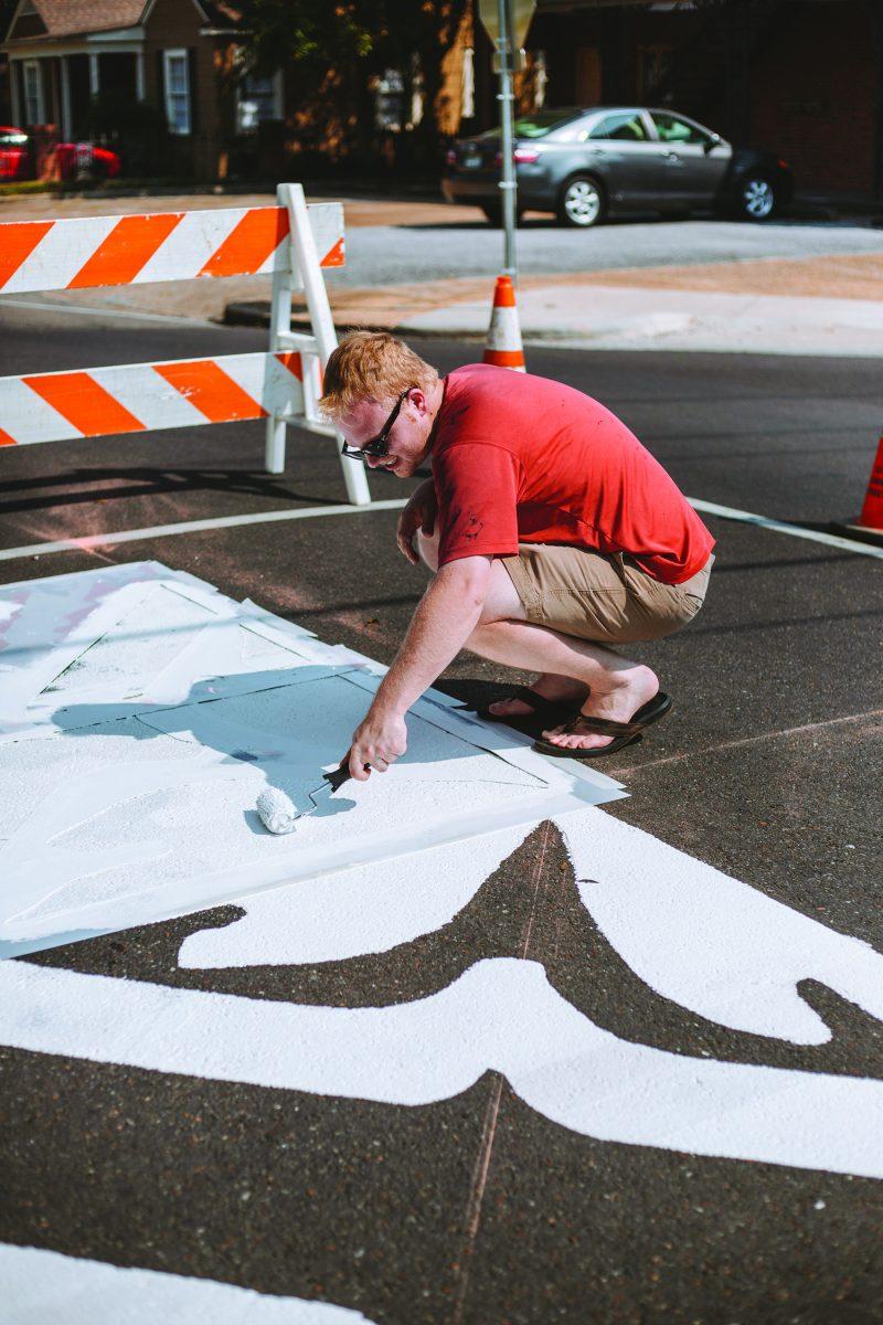 Starkville Central Neighborhood Foundation member Hagan Walker paints the Greensboro neighborhood crest on an intersection in the Greensboro Street Historic District on Sept. 8.