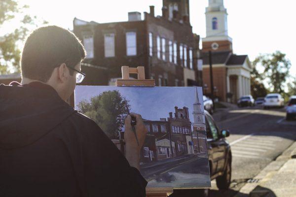 Garrett Seal, senior art major from Wiggins, Mississippi, paints a landscape of Lampkin Street in downtown Starkville. The student artist can often be found painting on Starkville street corners.