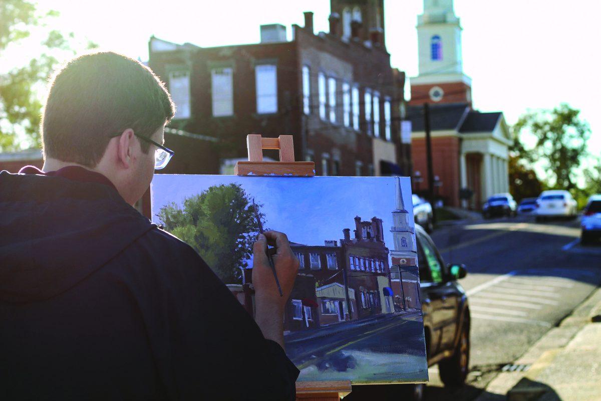 Garrett Seal, senior art major from Wiggins, Mississippi, paints a landscape of Lampkin Street in downtown Starkville. The student artist can often be found painting on Starkville street corners.