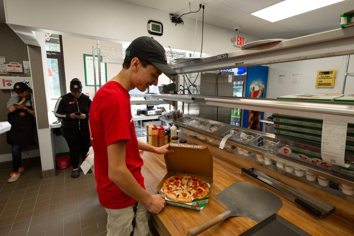 A crew member at Marco’s Pizza in Starkville prepares a pepperoni pizza for a customer.