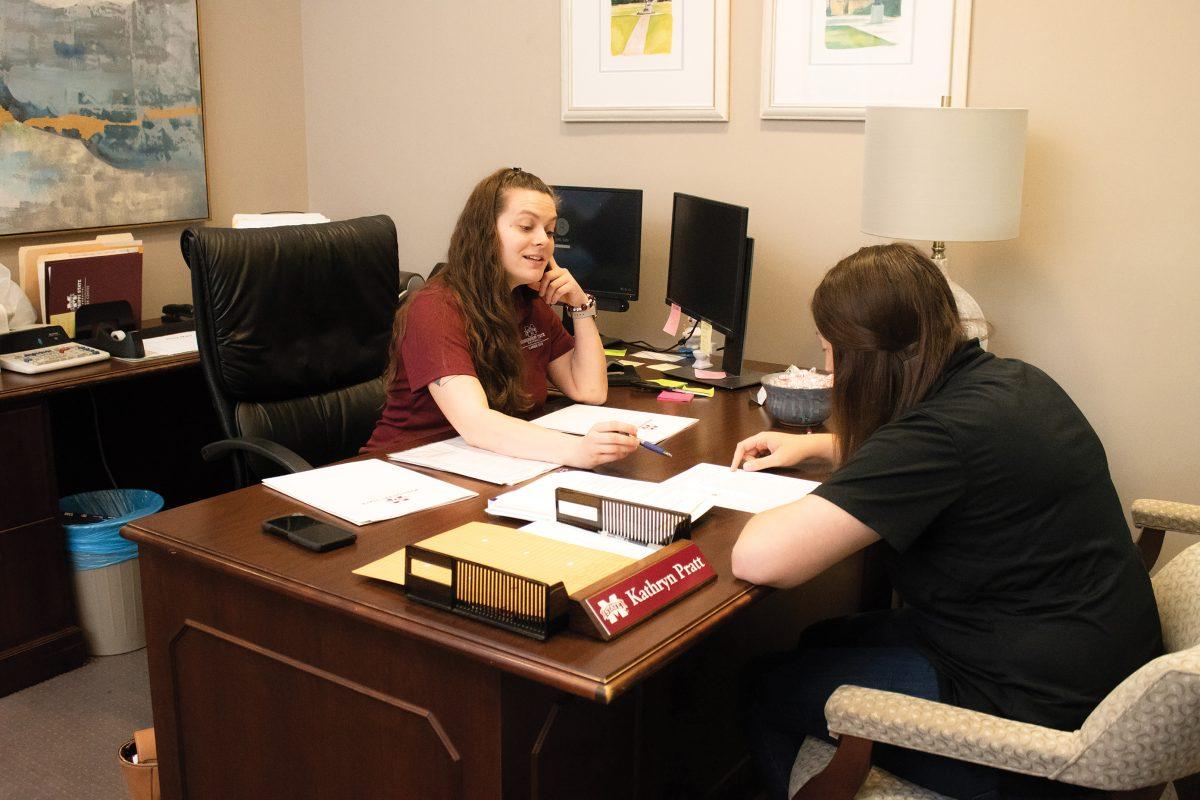 Kate Pratt works at the Career Center front desk as she talks to Courtney Eddy