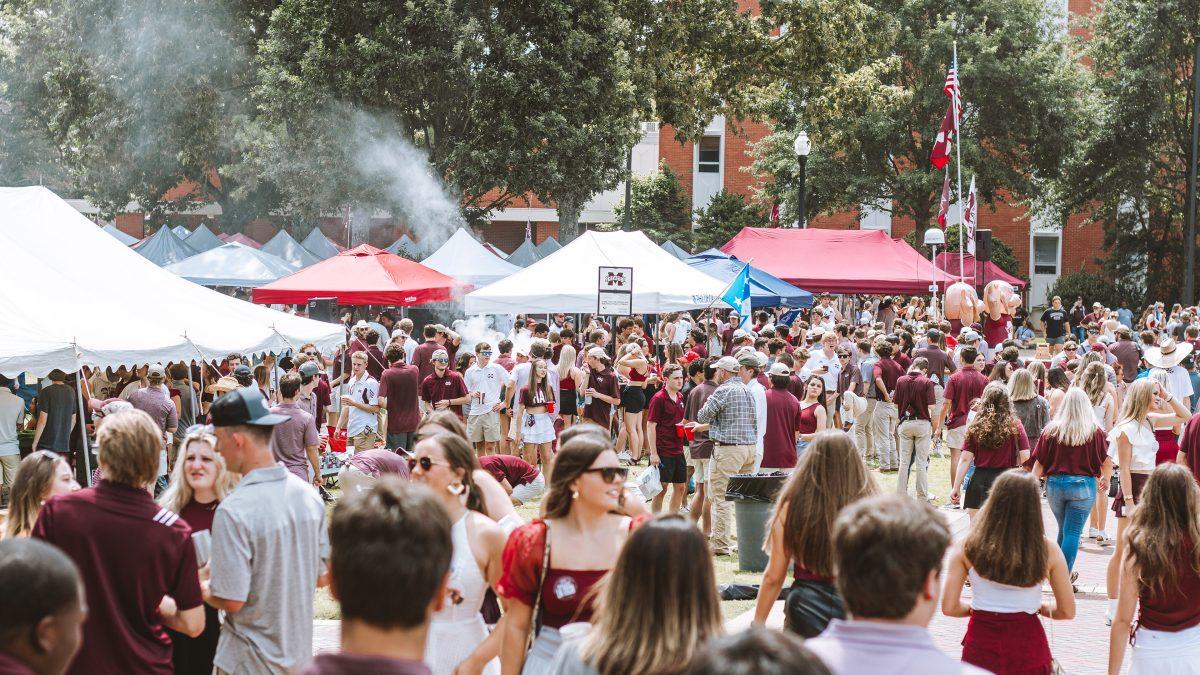 A crowd tailgates outside of Dorman Hall in MSU’s central tailgating spot, the Junction. The Junction sits in the shadow of Davis Wade Stadium, where cowbells are audible from inside.