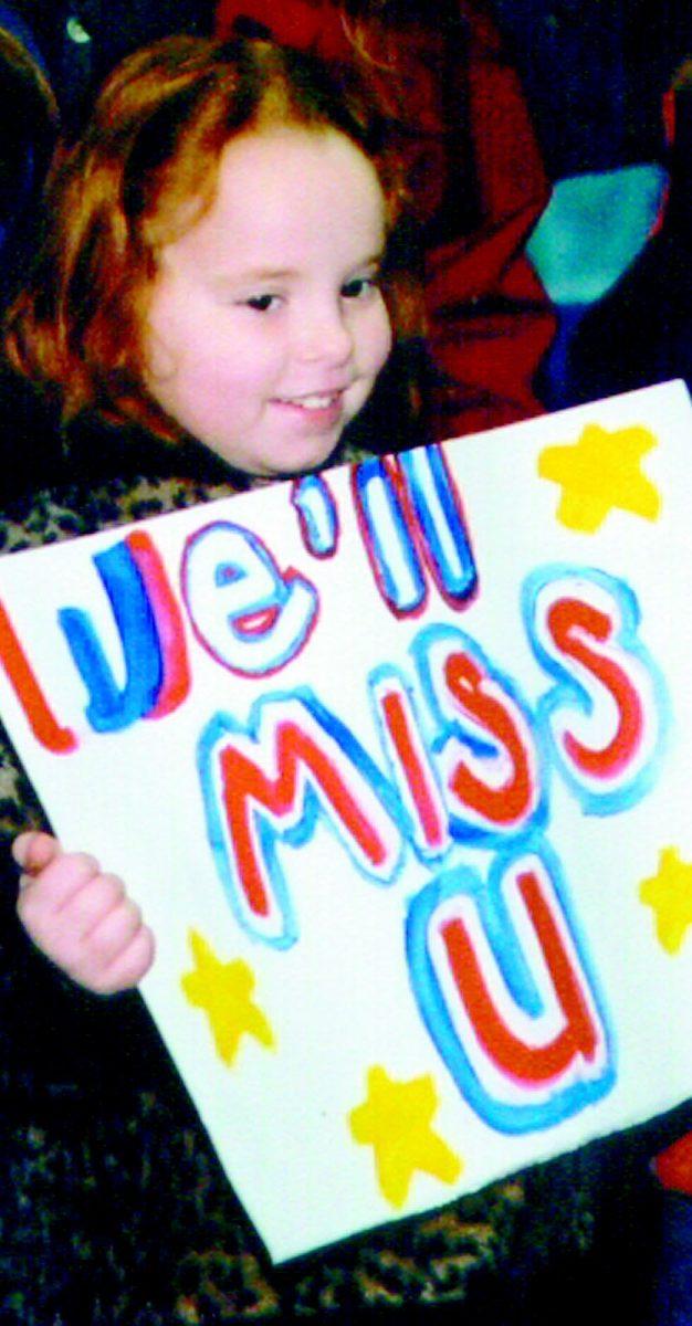 A young girl sends off her father, who is in the 113th military police detachment, with a poster.