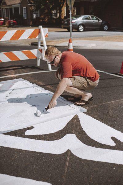 Starkville Central Neighborhood Foundation member Hagan Walker paints the Greensboro neighborhood crest on an intersection in the Greensboro Street Historic District on Sept. 8.