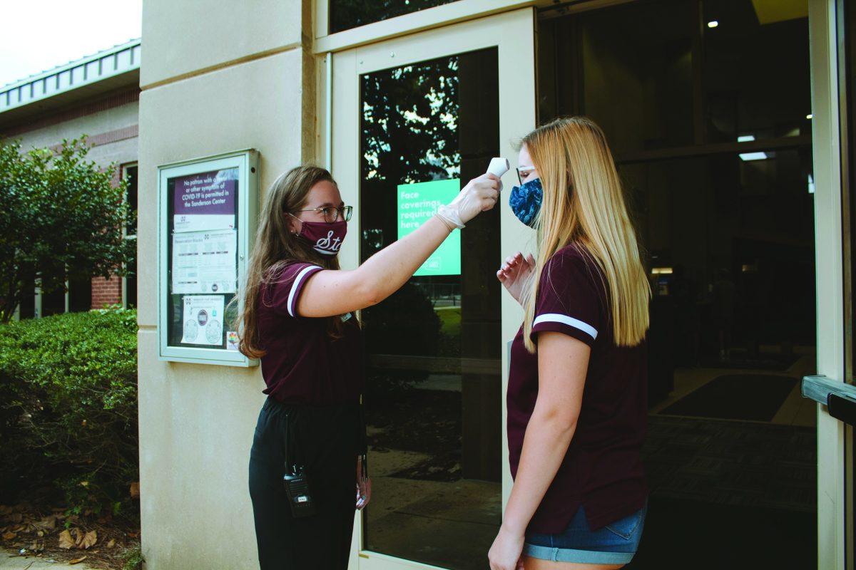 Senior Bettina Haden screens Paige LaPortes temperature as she enters the Sanderson Center in order to follow safety guidelines for COVID-19.