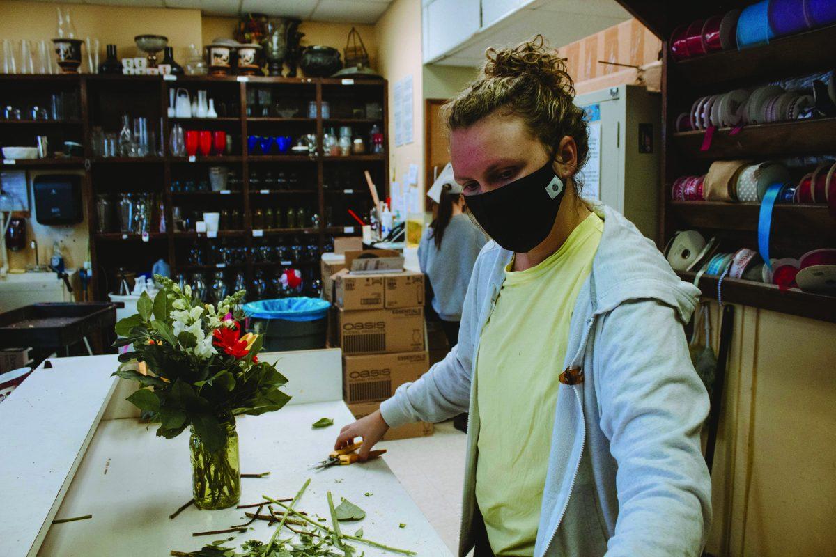 A student worker at the University Florist prepares a floral arrangement. The students handle a large amount of the responsibilities.