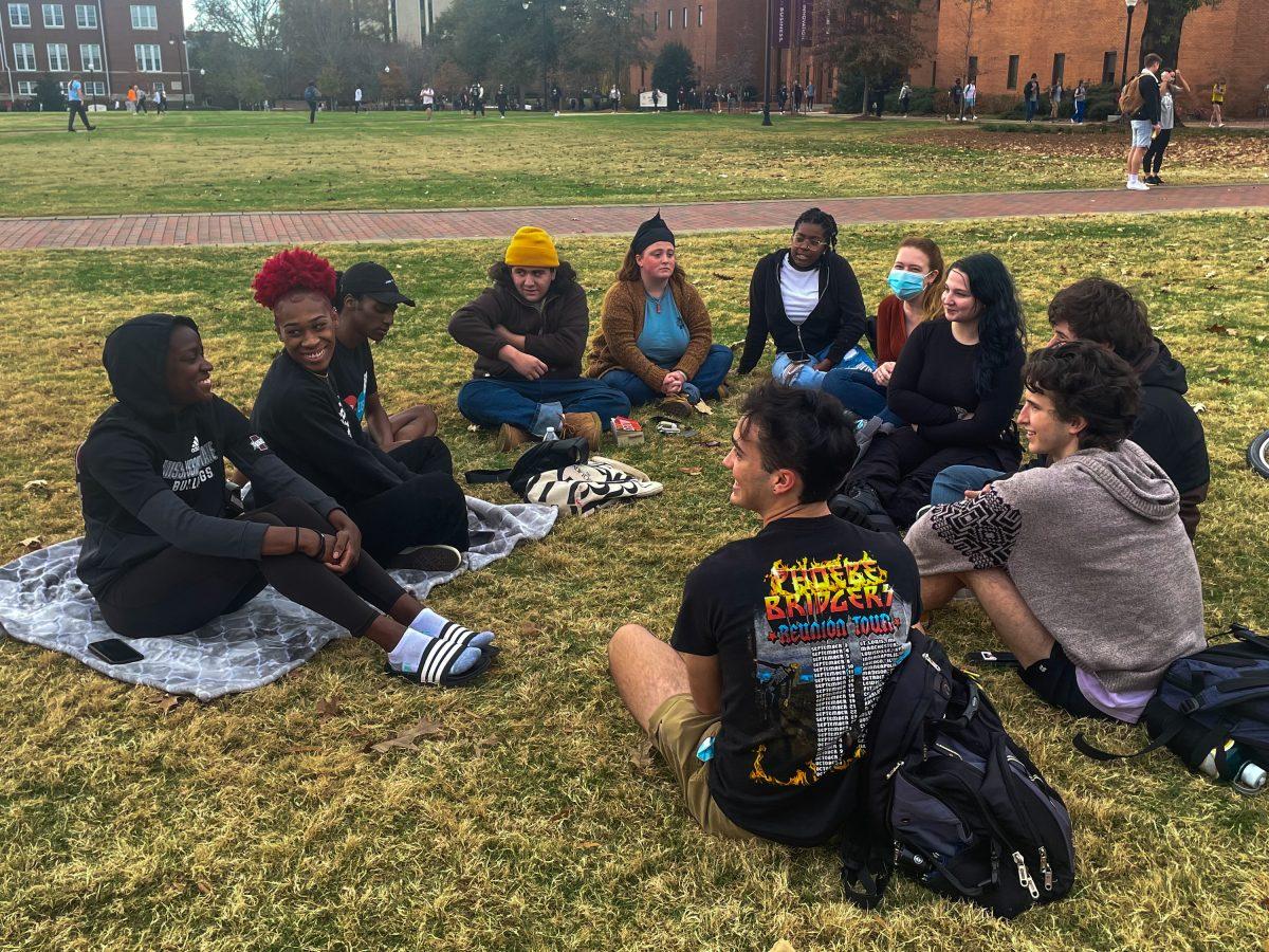 A group of protestors sit on the Drill Field Wednesday afternoon. Cat Moore, second from the left, organized the sit-in after the jury acquitted Kyle Rittenhouse of all charges a couple weeks ago.