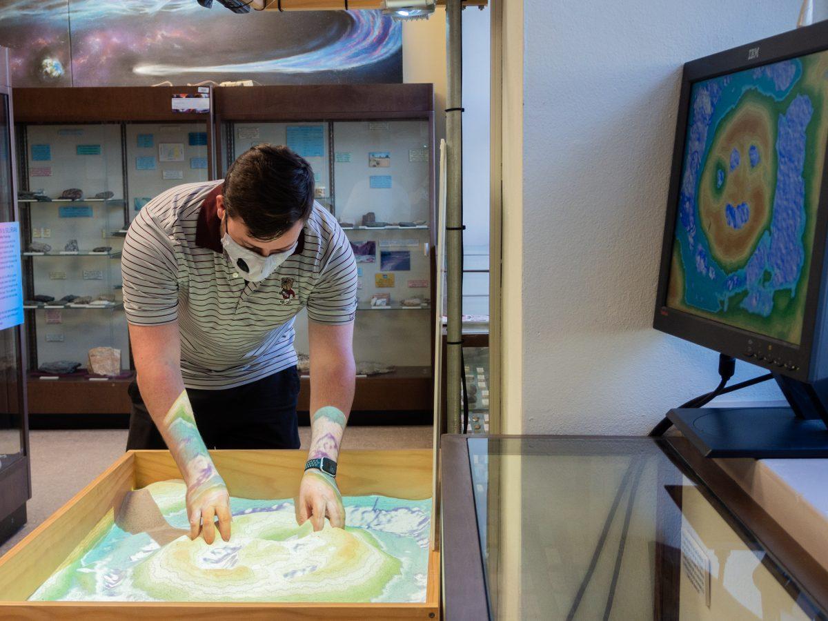 MSU student Andrew Dotson uses the interactive topographic map in the Dunn Seiler Museum.
