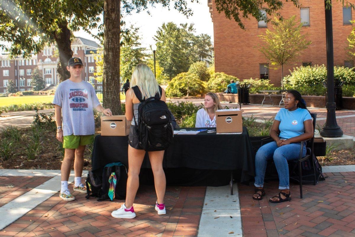 Groups of students from a legislative process class table around the Drill Field encouraging students to register to vote.