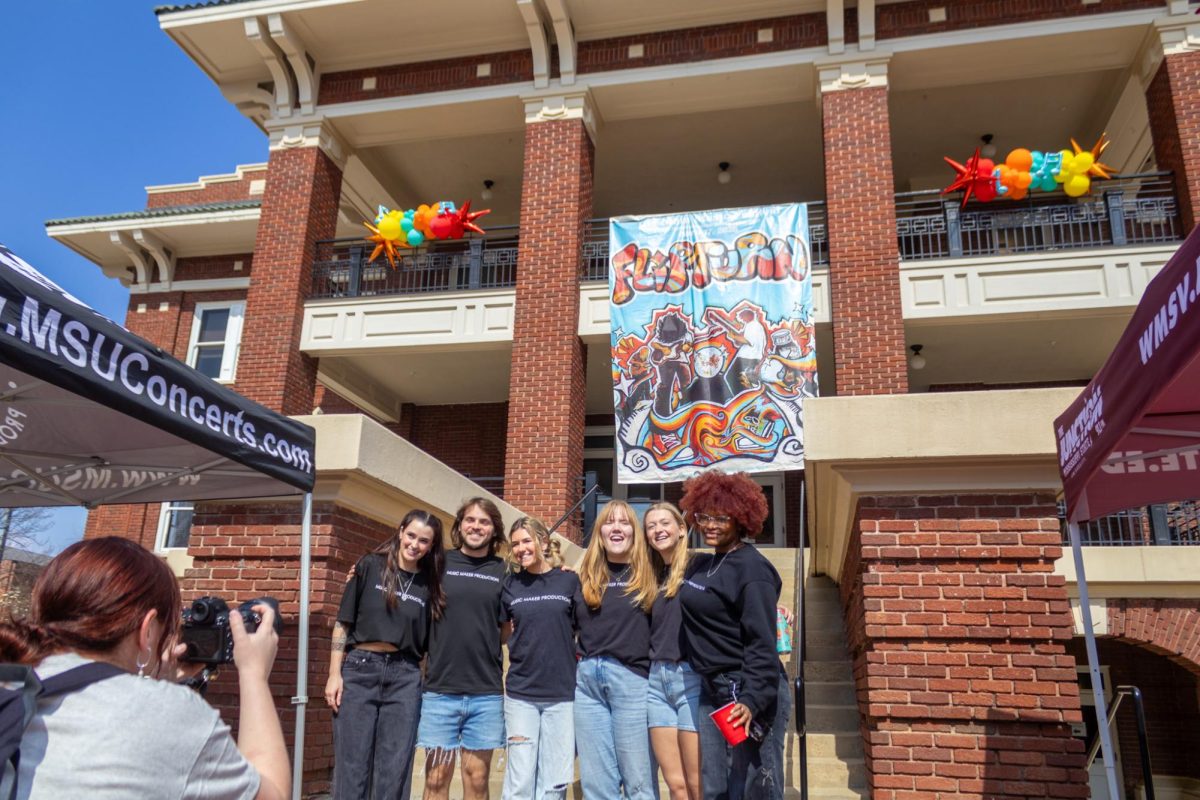 Music Maker Productions members unraveled a banner from the balcony of the YMCA building on Thursday to reveal Flipturn as the headliner for Old Main Music Festival.