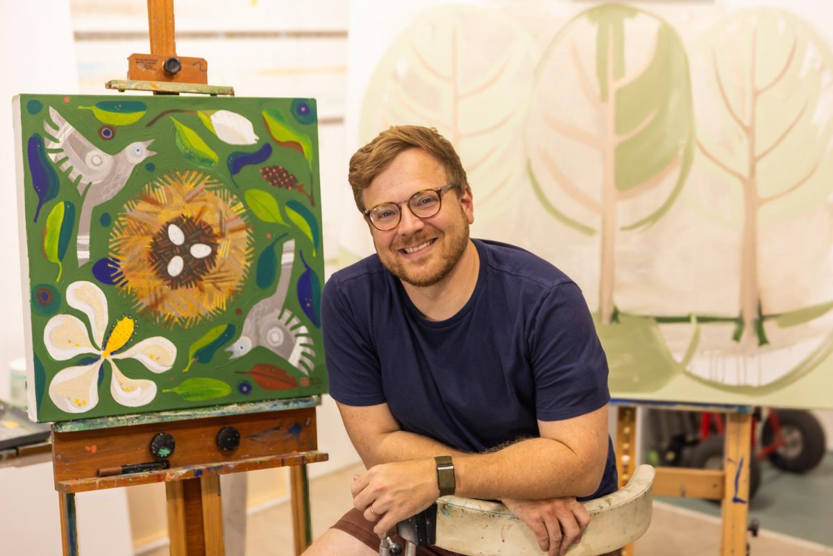 MSU alumnus Adam Trest poses for a photo taken by Brooke Davis-Jefcoat by his paintings.