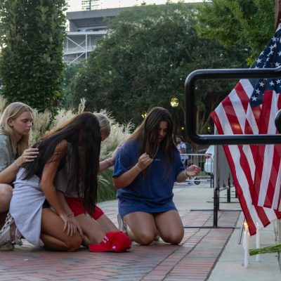 Students kneels in prayer during a vigil for Charlie Kirk on the YMCA Plaza on Wednesday night.